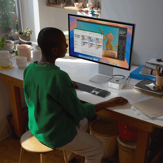 Una persona usa una Mac mini conectada a un monitor para trabajar en apps con una pantalla colorida